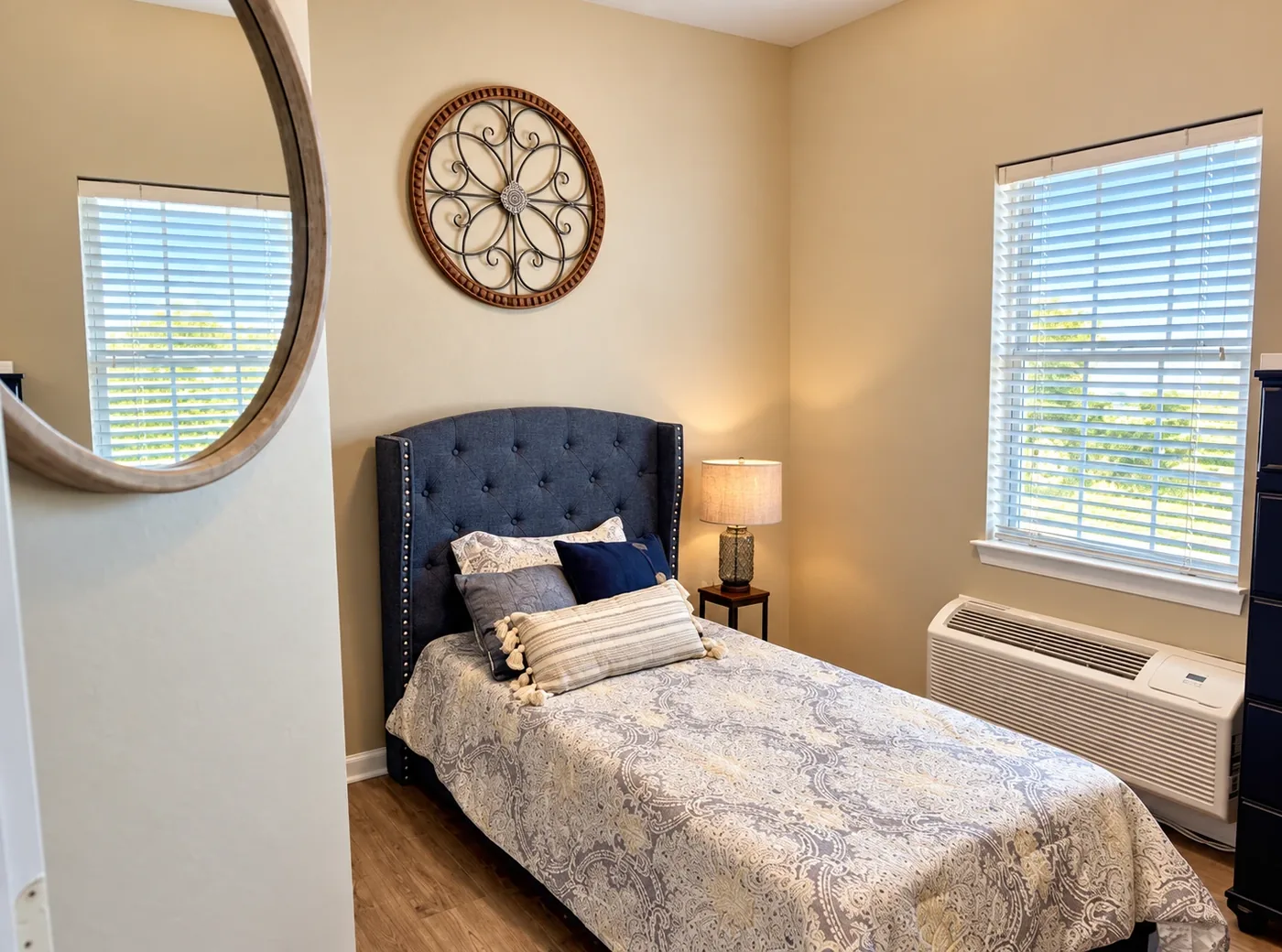 A Regency House bedroom with a tufted headboard, paisley bedspread and a bright window