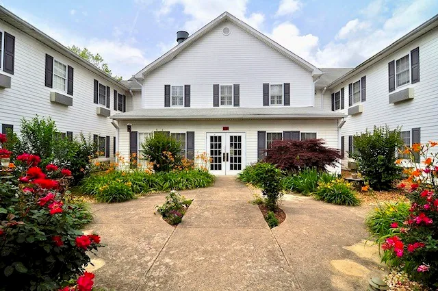 The Regency House courtyard in bloom, with red roses and daylilies along the walkway