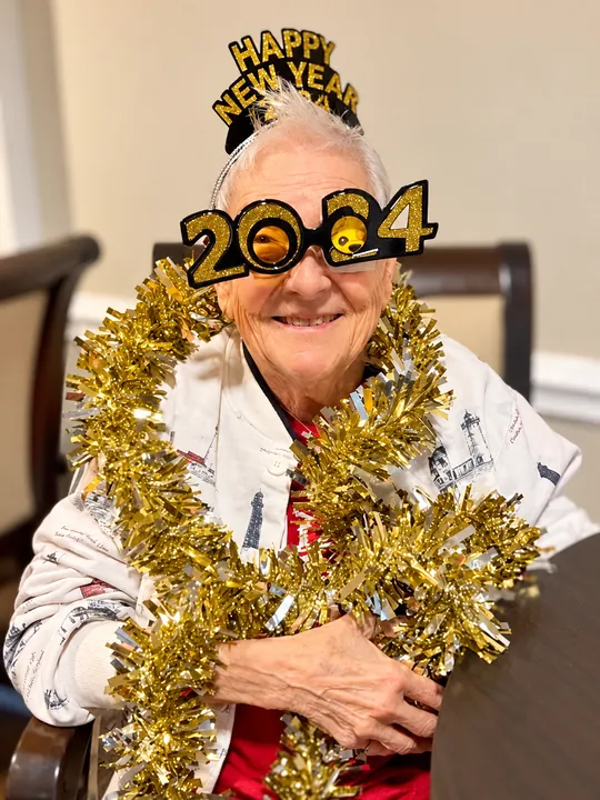 A resident in Happy New Year glasses and gold tinsel, smiling