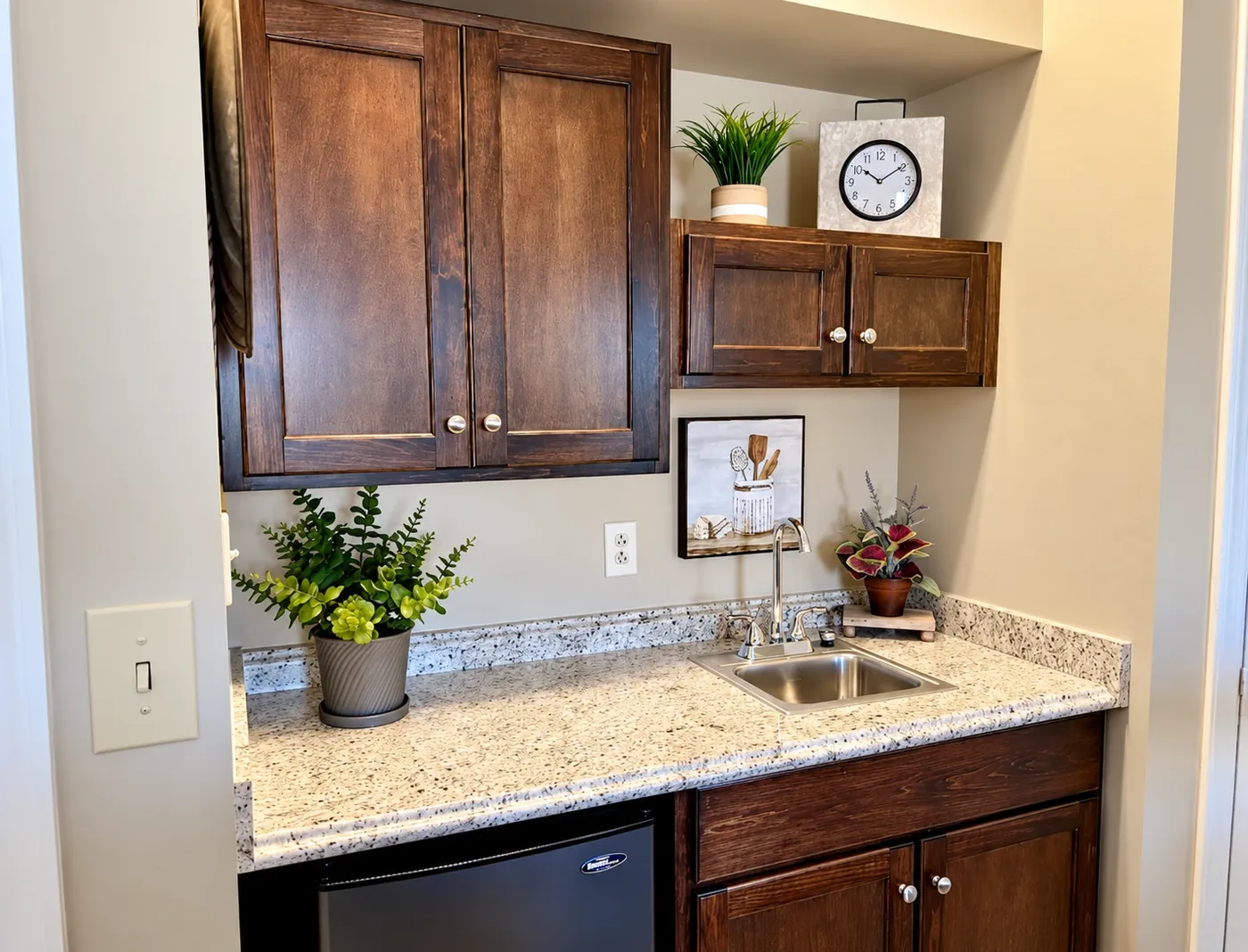 The kitchenette in a Regency House apartment, with wood cabinetry, granite counter, sink and refrigerator